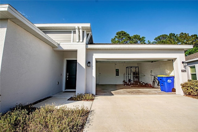 entrance to property with a garage, stucco siding, and driveway