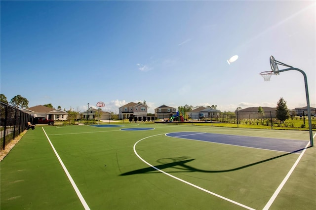 view of basketball court with fence, community basketball court, playground community, and a residential view