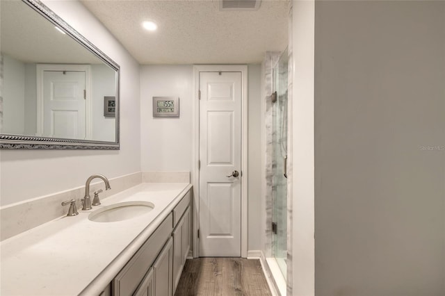full bathroom with a stall shower, wood finished floors, a textured ceiling, and vanity