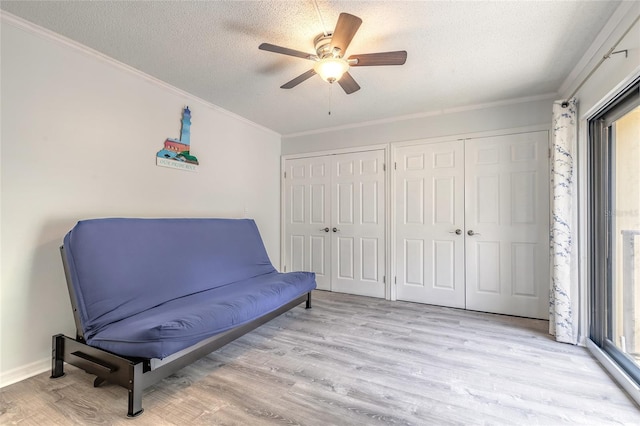 sitting room featuring light wood finished floors, ceiling fan, crown molding, and a textured ceiling