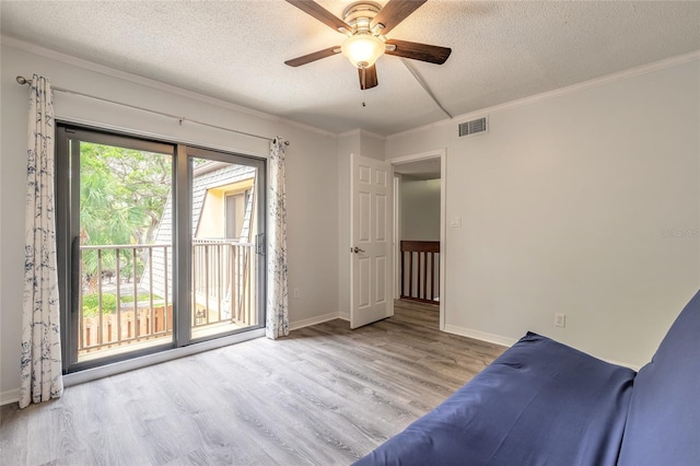 interior space with wood finished floors, a ceiling fan, a textured ceiling, ornamental molding, and baseboards