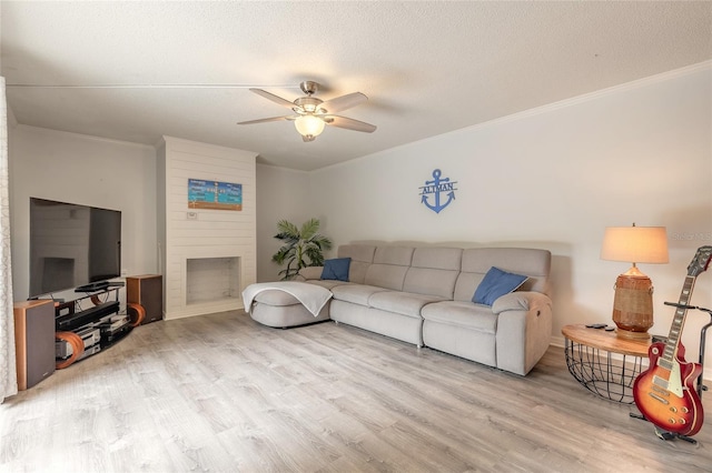 living room with crown molding, wood finished floors, a ceiling fan, a fireplace, and a textured ceiling