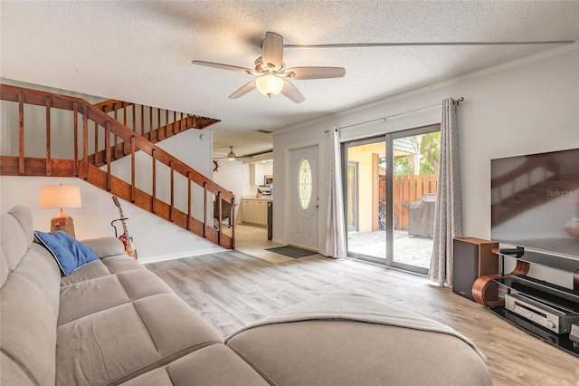 living room featuring ceiling fan, wood finished floors, stairway, a textured ceiling, and baseboards