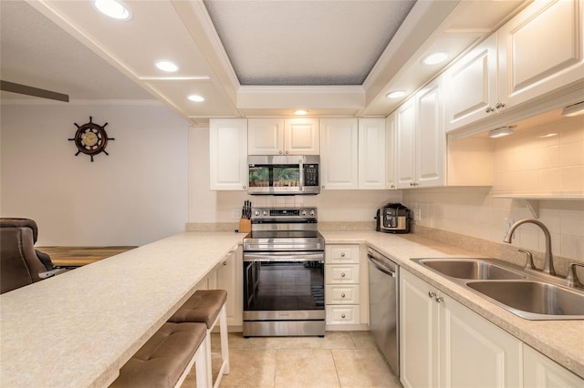 kitchen with stainless steel appliances, a sink, crown molding, light countertops, and recessed lighting