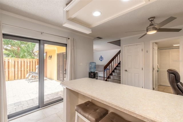 kitchen featuring a ceiling fan, light tile patterned floors, light countertops, ornamental molding, and a textured ceiling