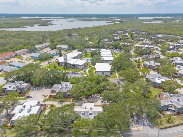 aerial view of property's location featuring a nearby body of water, nearby suburban area, and a forest
