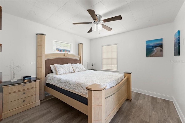 bedroom with baseboards, a ceiling fan, and dark wood-style floors