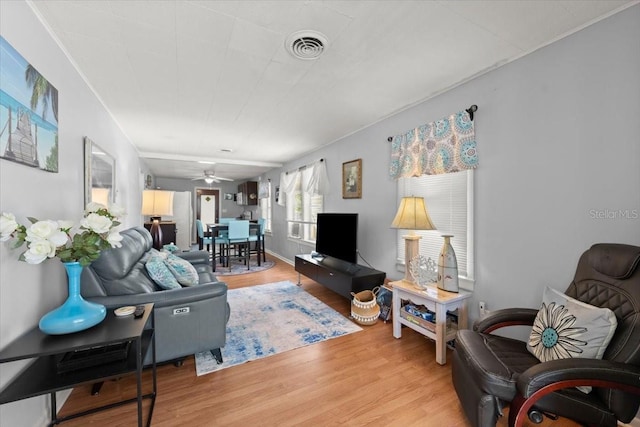 living area with ceiling fan, visible vents, and light wood-style floors