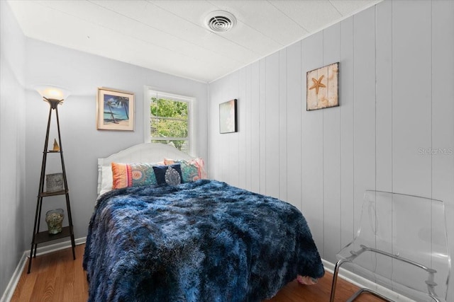 bedroom with baseboards, wood finished floors, and visible vents