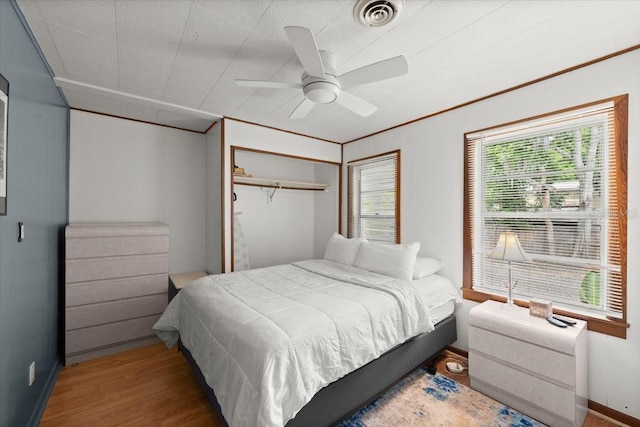 bedroom featuring visible vents, baseboards, ceiling fan, and wood finished floors