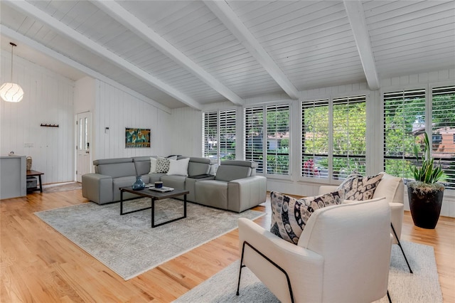 living area featuring lofted ceiling with beams, a healthy amount of sunlight, and wood finished floors