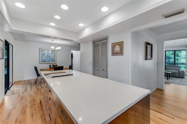 kitchen with an inviting chandelier, a center island, light wood-type flooring, visible vents, and light countertops