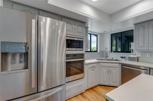 kitchen with light countertops, stainless steel appliances, a sink, and gray cabinets