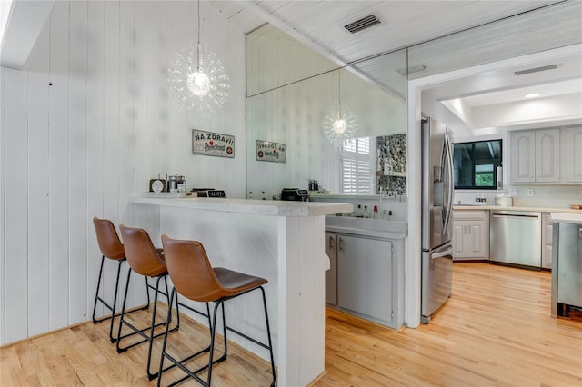 bar with light wood-style flooring, hanging light fixtures, an inviting chandelier, visible vents, and appliances with stainless steel finishes