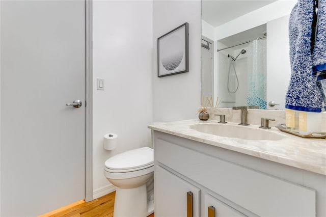 bathroom with toilet, curtained shower, wood finished floors, and vanity
