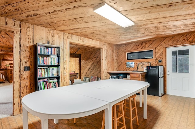 dining room with wood ceiling, wood walls, and light floors