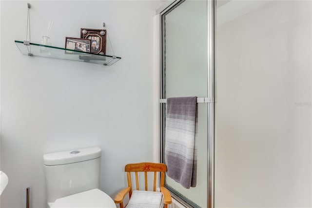 bathroom featuring a shower with shower door and toilet