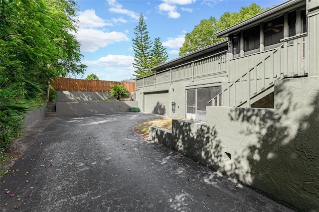 view of home's exterior with board and batten siding, aphalt driveway, a garage, and fence