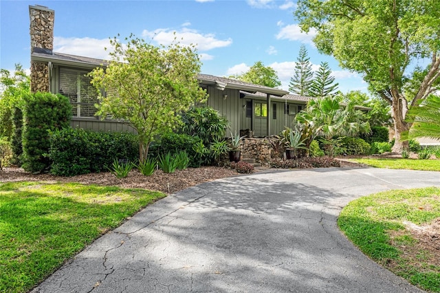view of front of property with driveway, a chimney, and a front yard