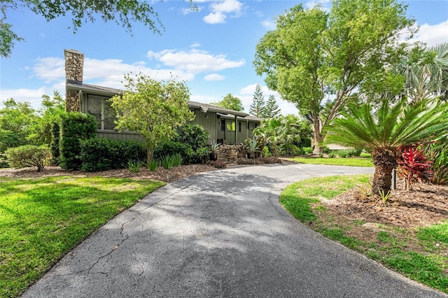view of home's exterior with a yard, a chimney, and curved driveway