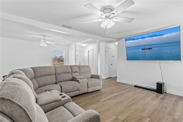 living area with baseboards, visible vents, light wood-style flooring, and a ceiling fan