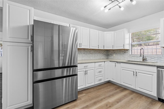 kitchen featuring a textured ceiling, white cabinets, appliances with stainless steel finishes, and a sink