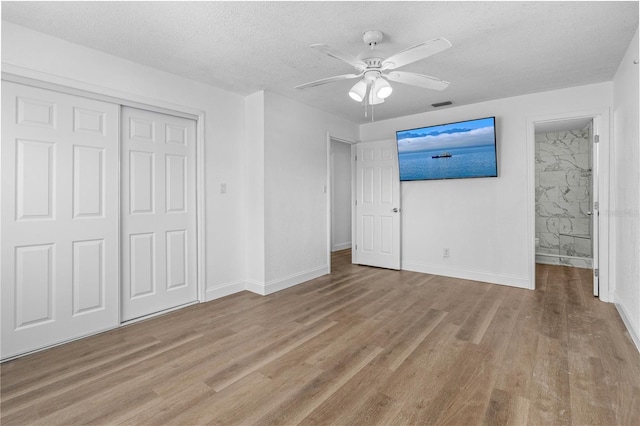 unfurnished bedroom with a textured ceiling, baseboards, a closet, and wood finished floors
