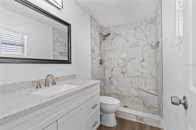 full bathroom with a stall shower, a textured ceiling, toilet, vanity, and wood finished floors
