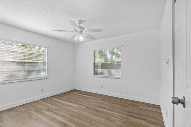 empty room with a textured ceiling, baseboards, a ceiling fan, and wood finished floors