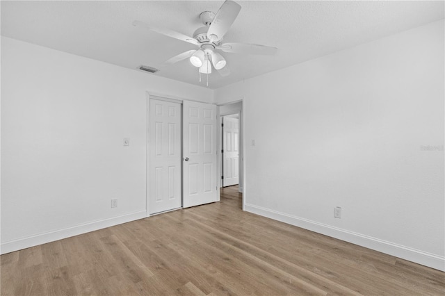 unfurnished bedroom featuring a closet, visible vents, ceiling fan, baseboards, and light wood-style floors