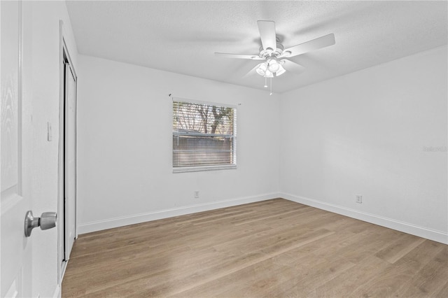 unfurnished bedroom featuring a closet, a textured ceiling, light wood finished floors, ceiling fan, and baseboards