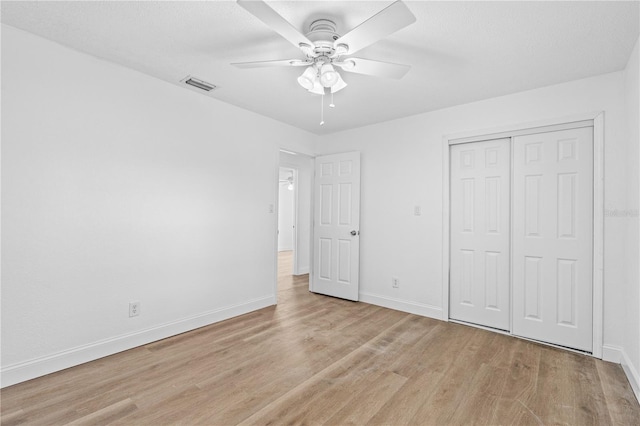 unfurnished bedroom featuring a closet, light wood-style floors, visible vents, and baseboards