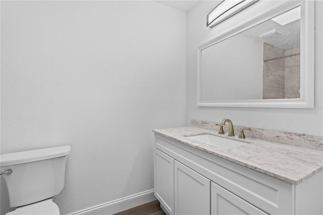 bathroom featuring vanity, toilet, baseboards, and wood finished floors