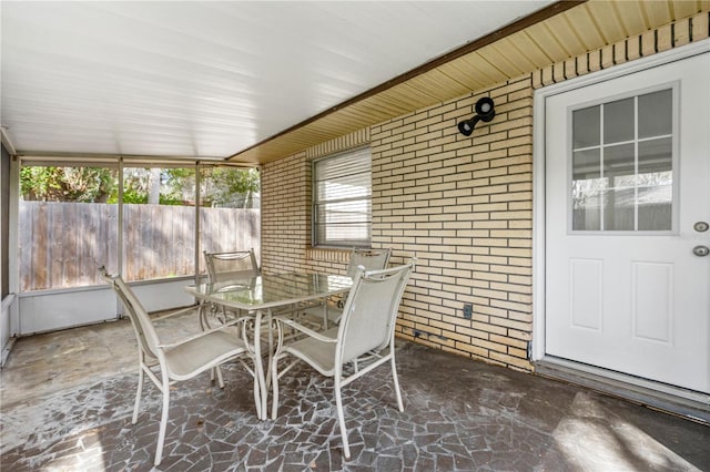 sunroom / solarium featuring brick wall and stone floors