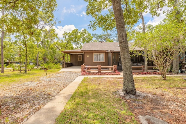 bungalow featuring driveway, an attached carport, board and batten siding, a sunroom, and a front yard