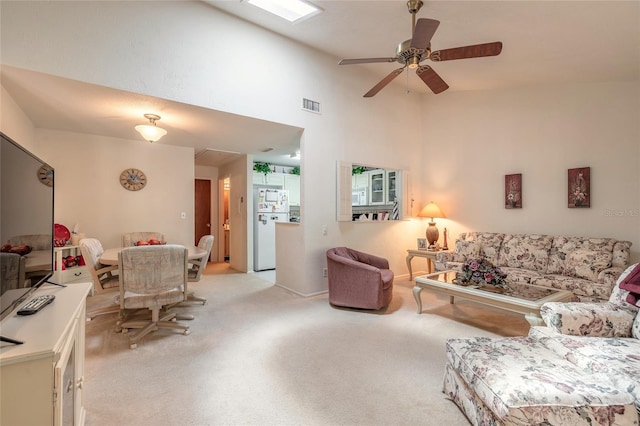 living area with light carpet, a ceiling fan, and high vaulted ceiling