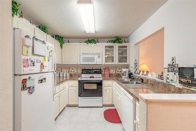 kitchen featuring white appliances, a sink, a textured ceiling, glass insert cabinets, and light tile patterned floors