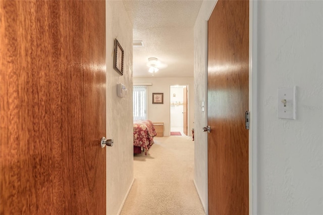 hall featuring a textured ceiling and carpet flooring