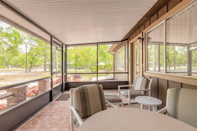 sunroom featuring view of wooded area
