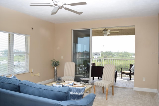 living room featuring a ceiling fan, light carpet, and baseboards