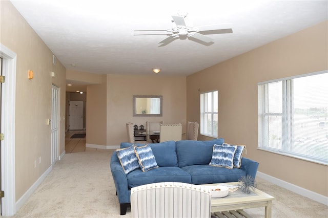 living area with light colored carpet, baseboards, and a ceiling fan