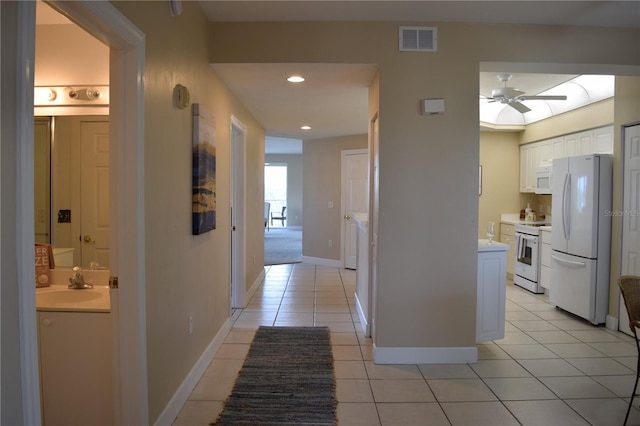 corridor featuring a sink, light tile patterned flooring, visible vents, recessed lighting, and baseboards