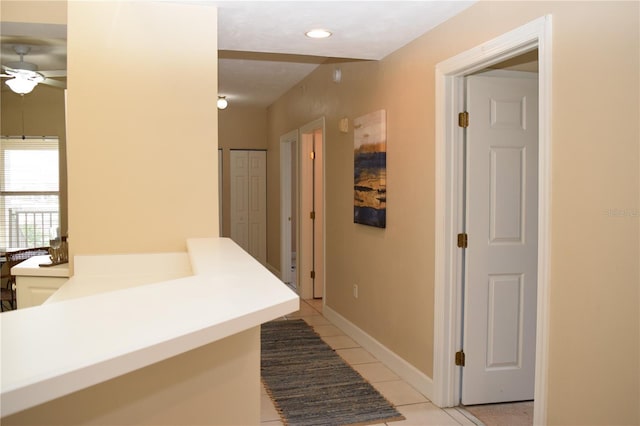 hall featuring light tile patterned floors, baseboards, and recessed lighting
