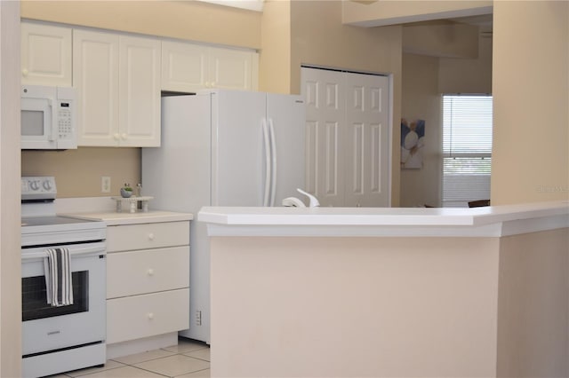 kitchen with light tile patterned floors, white appliances, light countertops, and white cabinetry