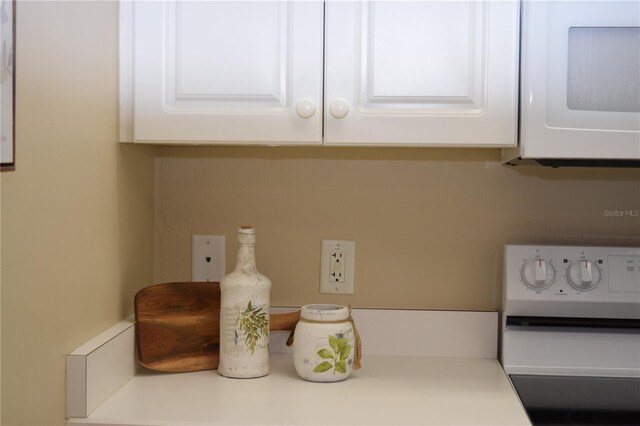 details featuring white cabinets, range, light countertops, and white microwave