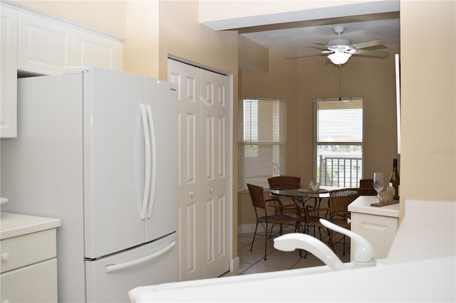 kitchen featuring freestanding refrigerator, light tile patterned floors, ceiling fan, light countertops, and white cabinets