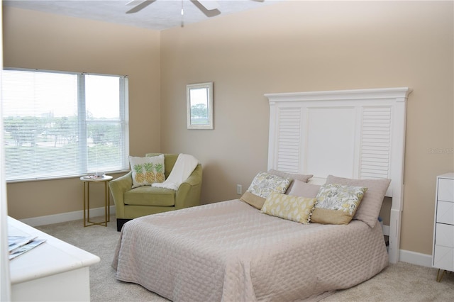 bedroom with ceiling fan, light carpet, and baseboards
