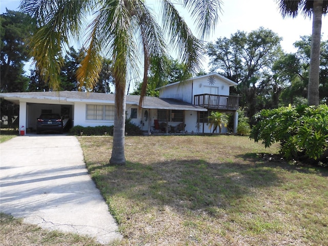 view of front of property featuring concrete driveway, a front lawn, and a carport