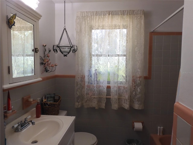bathroom featuring tile walls, toilet, vanity, shower / bathtub combination, and a wainscoted wall