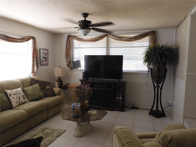 living area with a textured ceiling, tile patterned floors, healthy amount of natural light, and a ceiling fan
